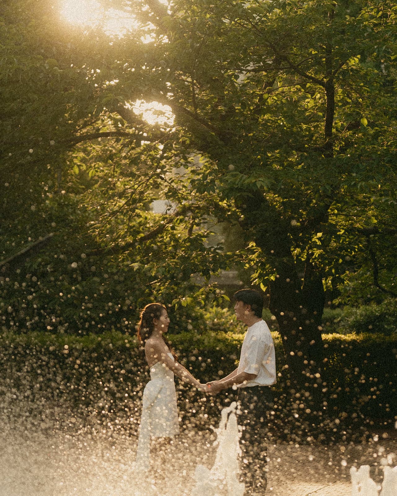 Holding hands by a fountain at golden hour