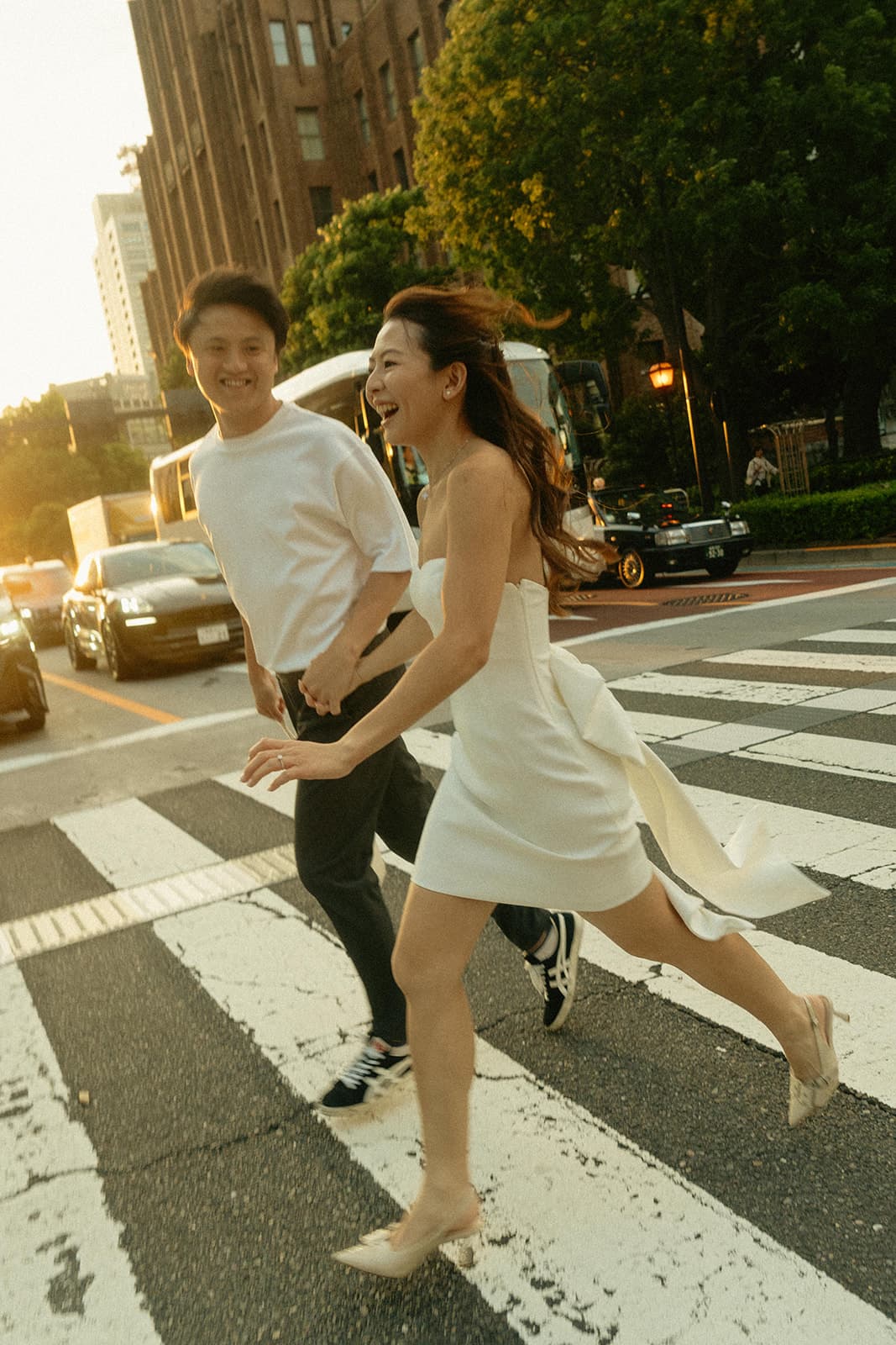 Belinda and Jia Jing running across a Tokyo crosswalk at sunset