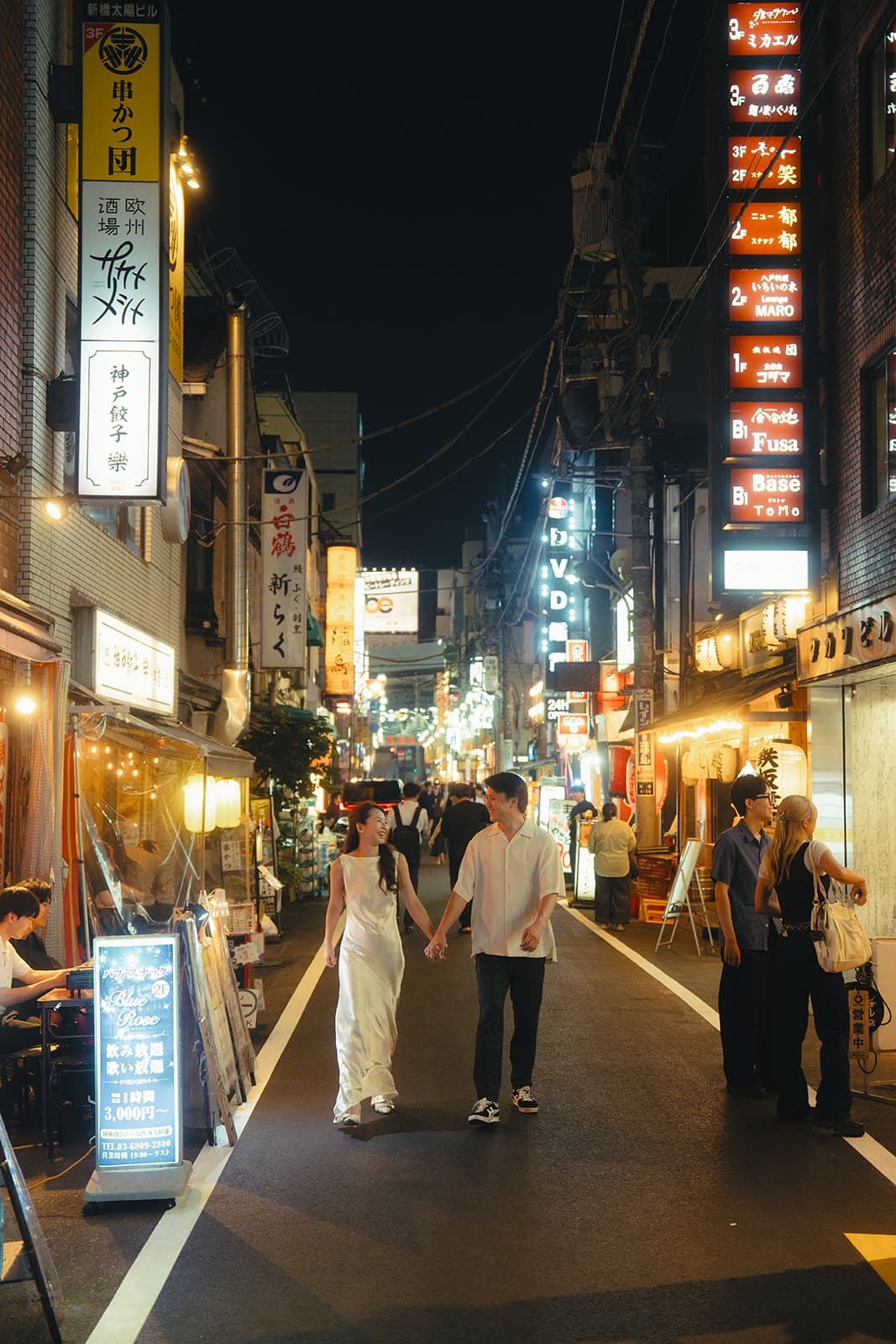 Walking hand in hand through a lantern-lit Tokyo street